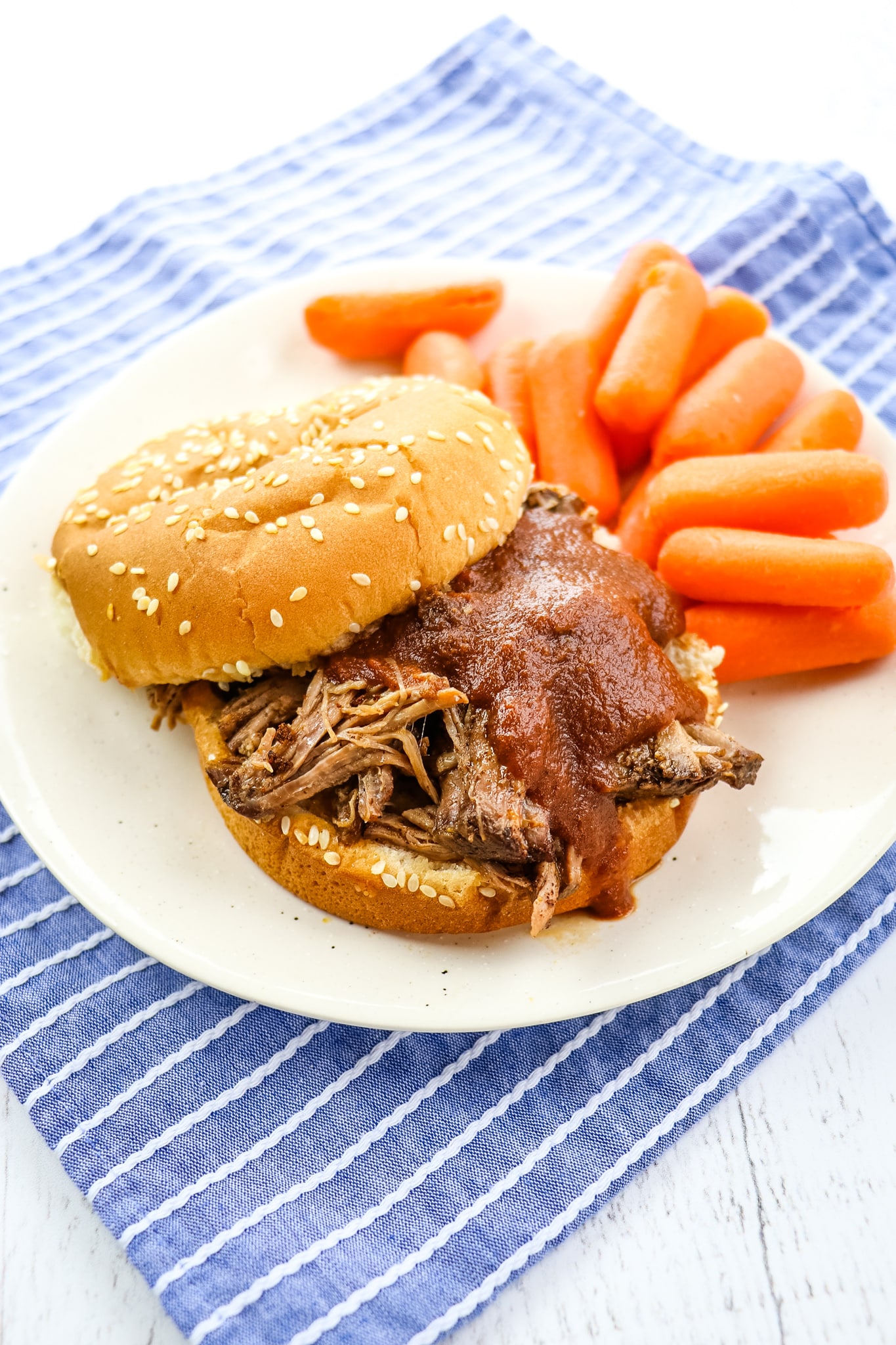 Pulled beef sandwiches on plate with carrots.