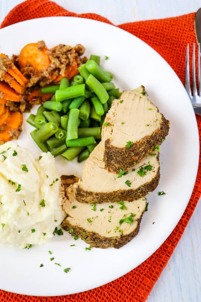 Slow cooker turkey breast on plate with potatoes, green beans and sweet potatoes.