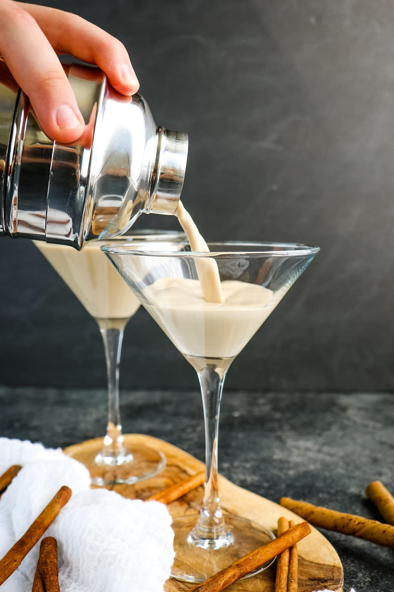 Tiramisu cocktail being poured into a martini glass from cocktail shaker.