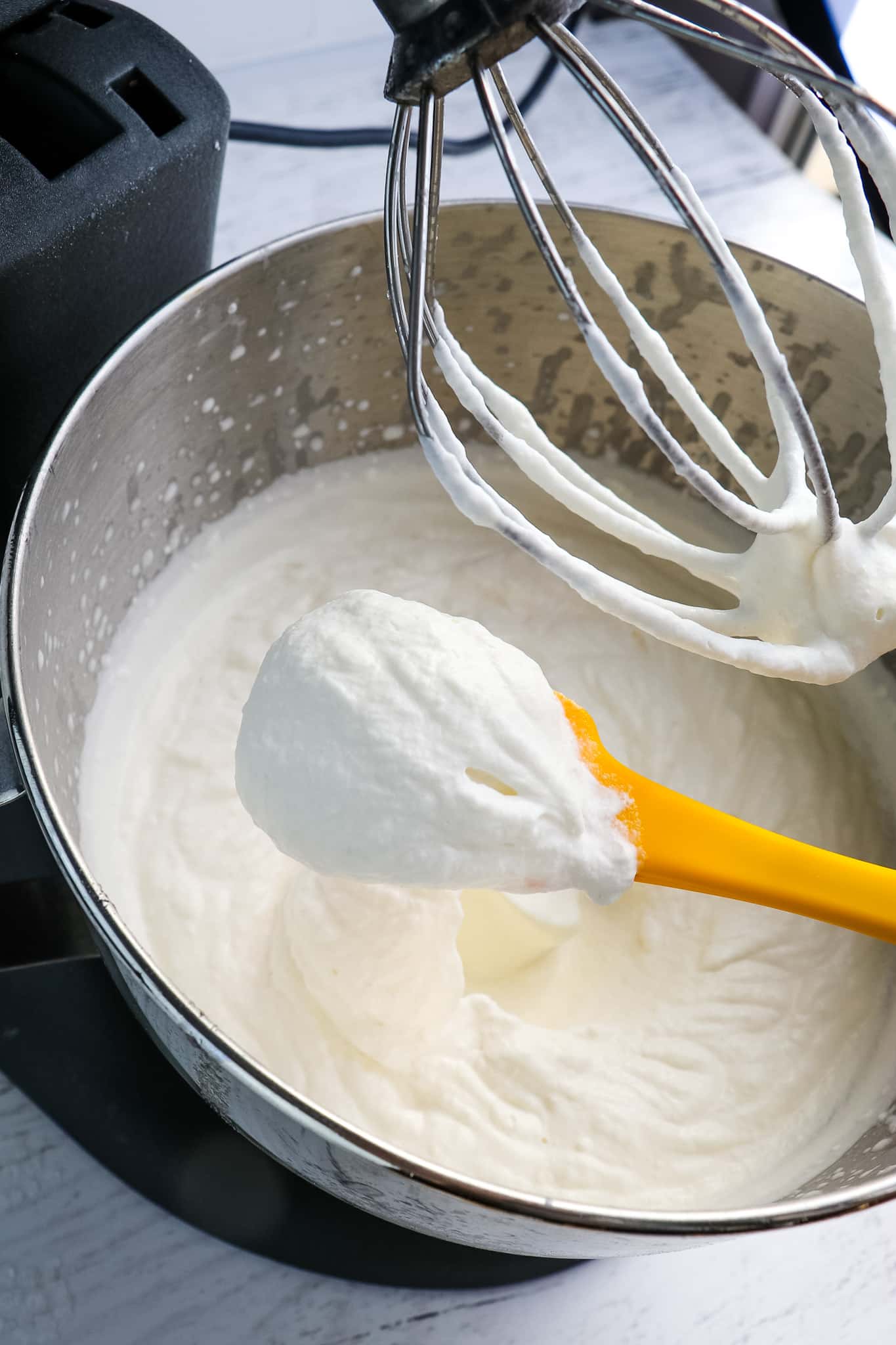 Homemade cool whip recipe in mixing bowl, with scoop of cream.