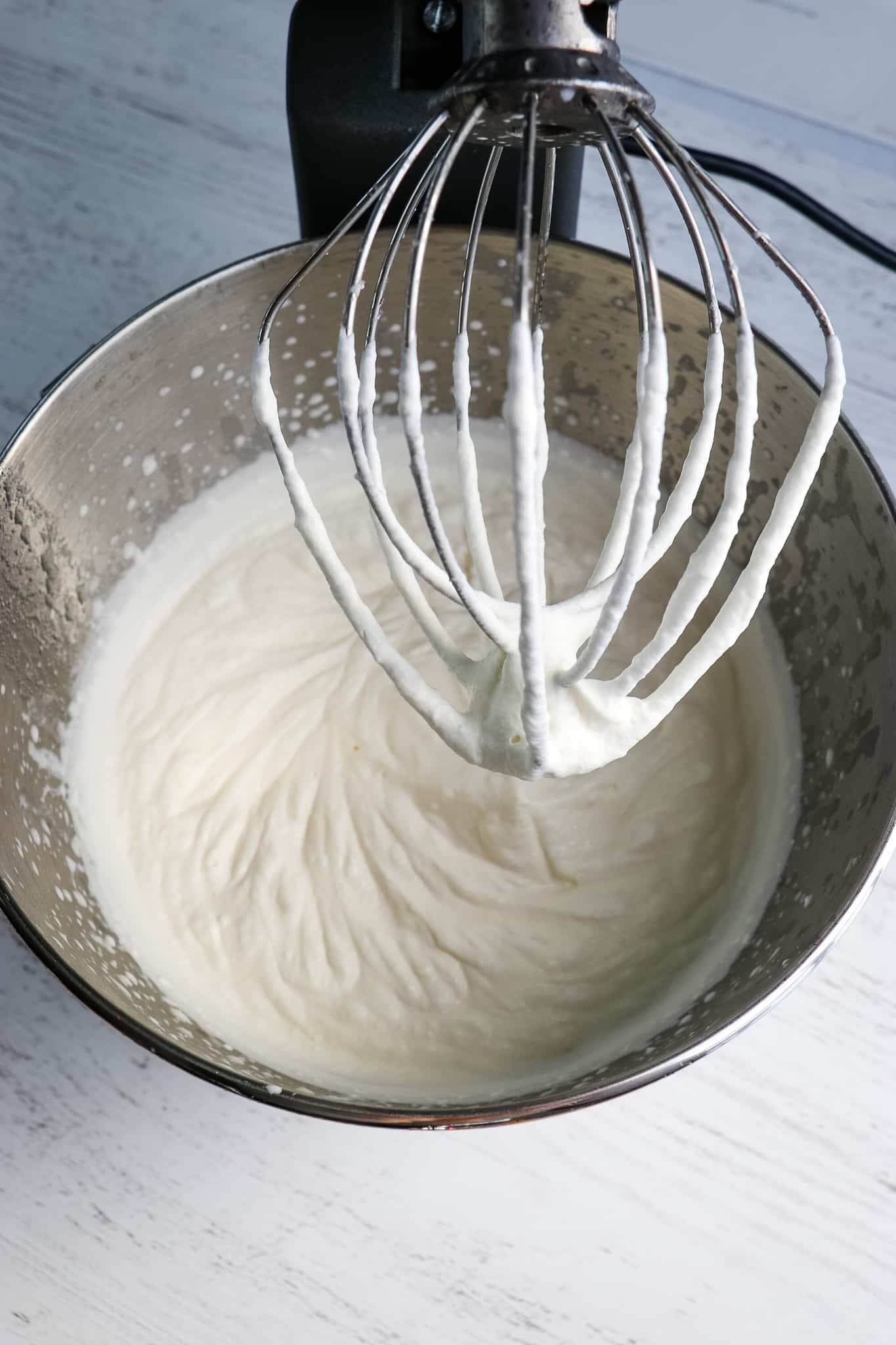 Homemade cool whip recipe in mixing bowl with whisk attachment.