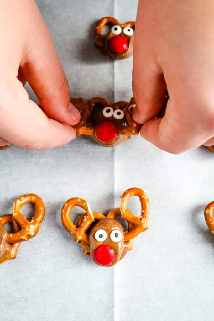 Placing broken pretzel halves into rolos for reindeer pretzels.