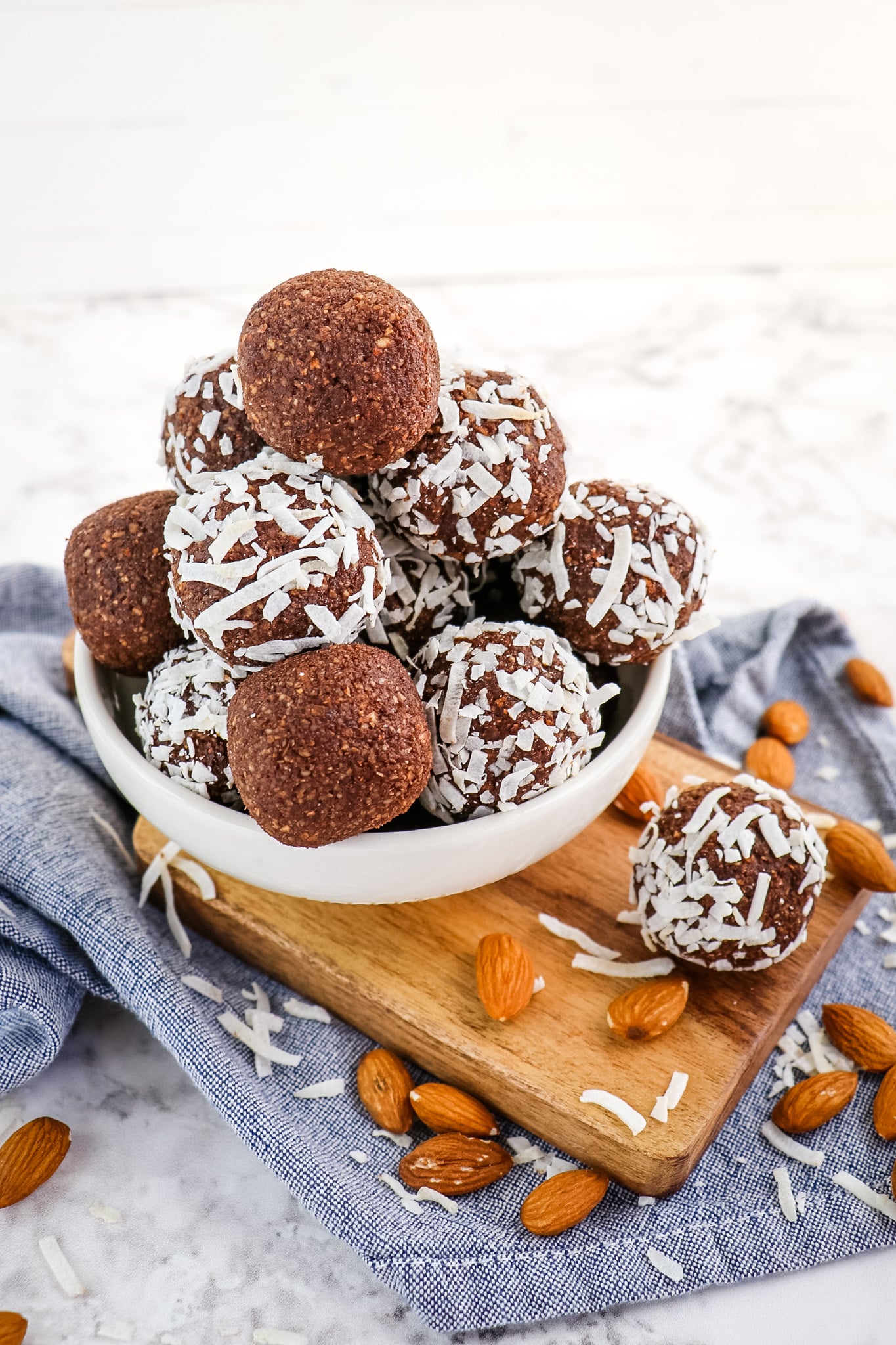 Chocolate coconut date balls in bowl garnished with almonds and coconut.