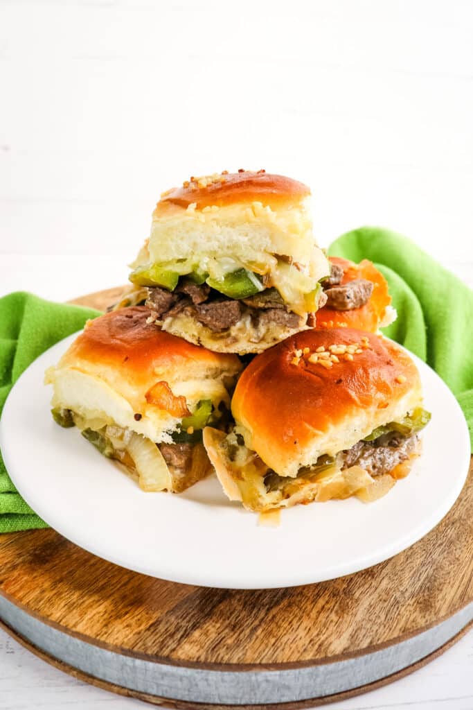 Stack of cheesesteak sliders stacked on a white plate.