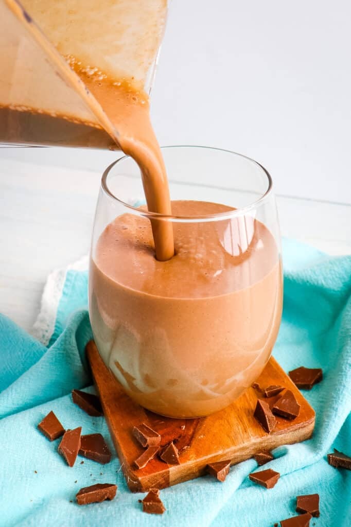 Chocolate peanut butter banana smoothie being poured into a glass.