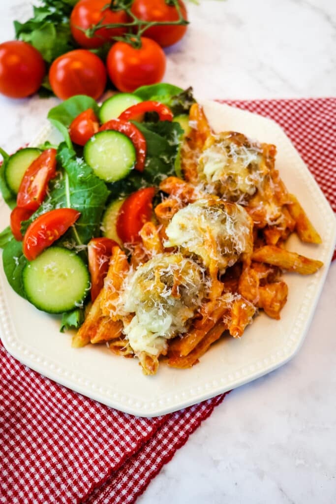 Serving of meatball casserole recipe on plate with green salad.