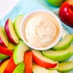 Greek yogurt fruit dip in a bowl with green and red apple slices on the side.