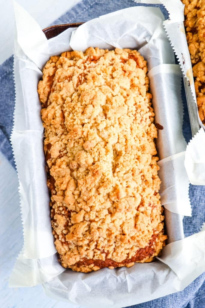 Baked loaf of award winning banana bread in pan with parchment paper.