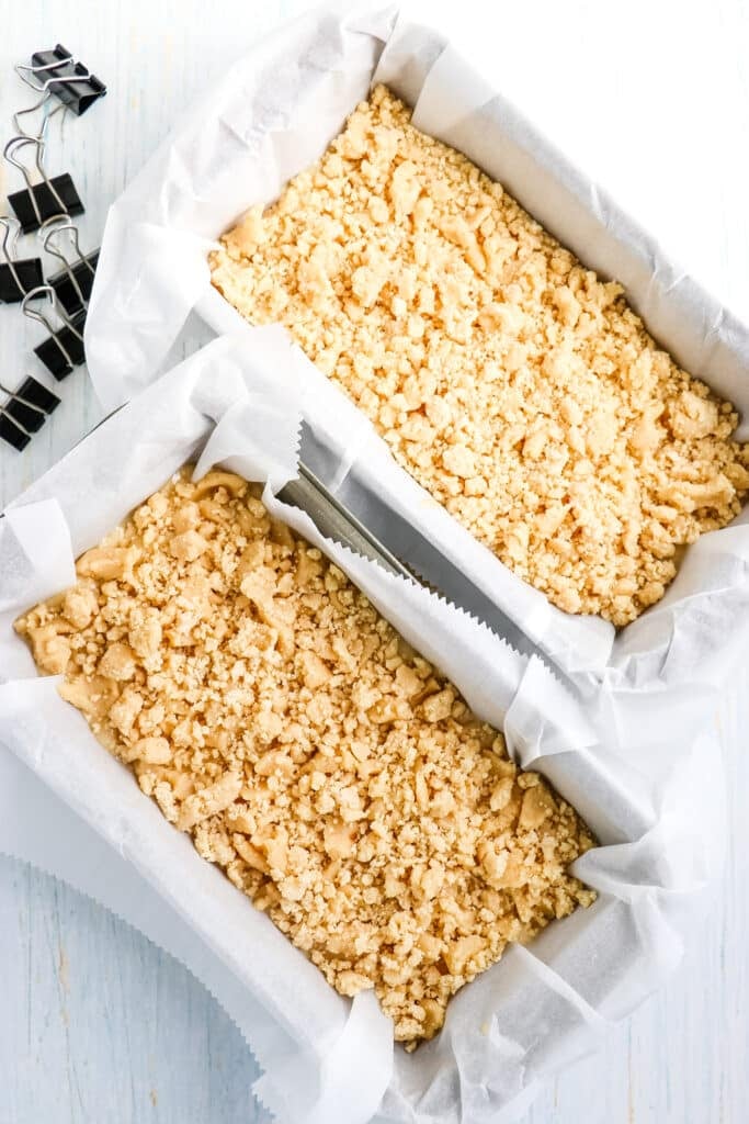 Banana bread batter in two loaf pans, topped with crumble topping.