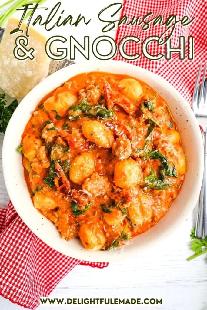 Bowl of sausage gnocchi with sun dried tomatoes and spinach in a creamy red sauce.