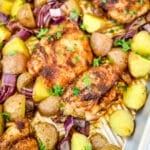 Roasted chicken thighs and potatoes on sheet pan topped with chopped parsley.