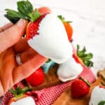 White chocolate covered strawberry being held in hand.