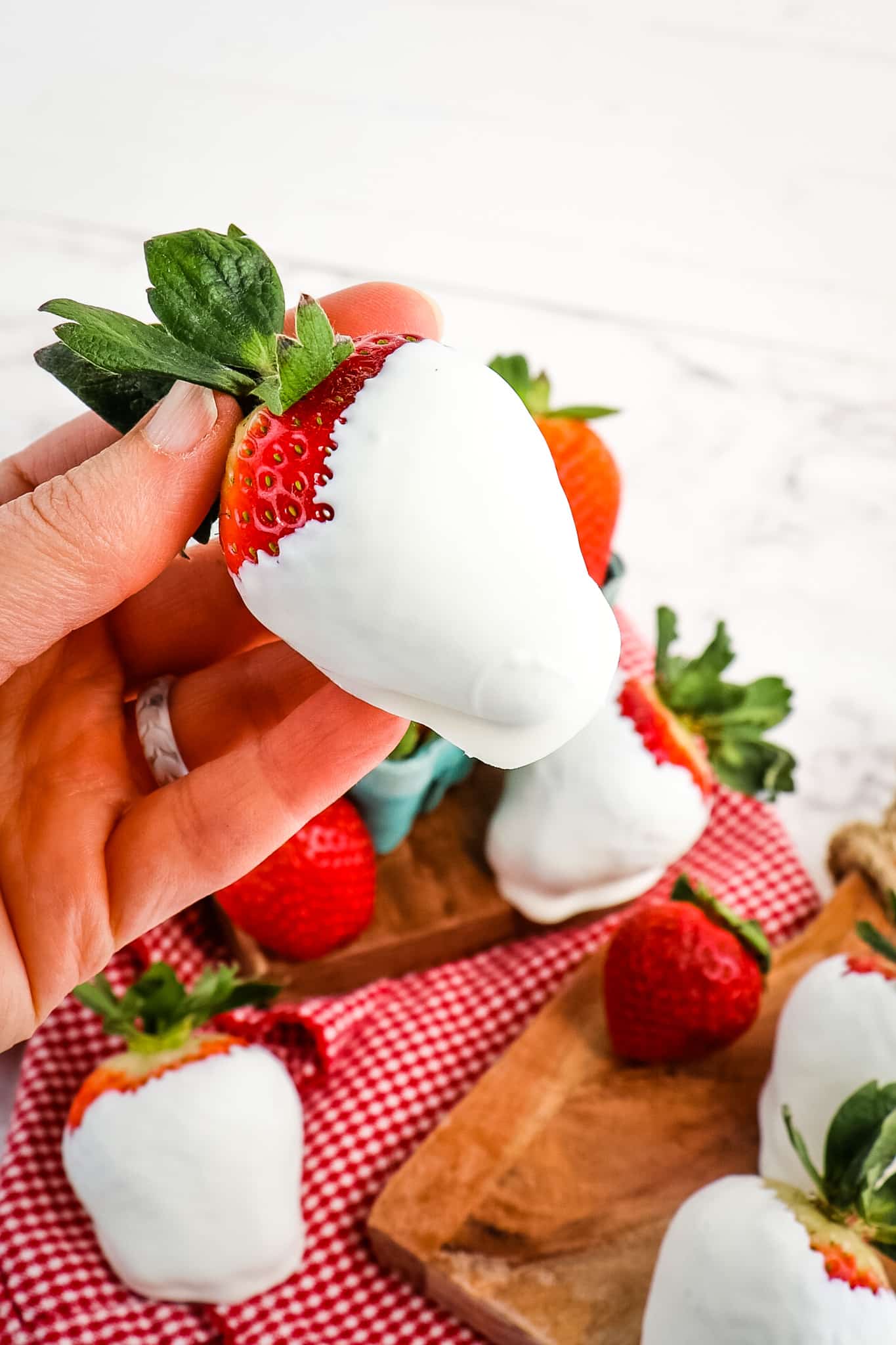 White chocolate covered strawberry being held in hand.