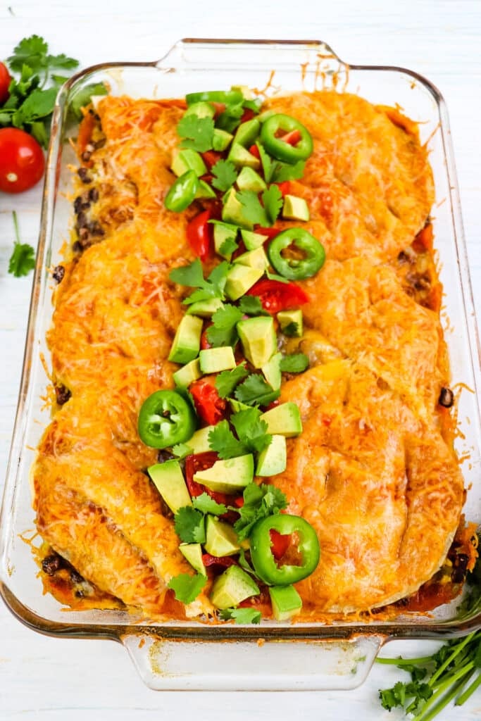 Baked beef enchilada casserole recipe topped with avocados, tomatoes and sliced jalapenos.