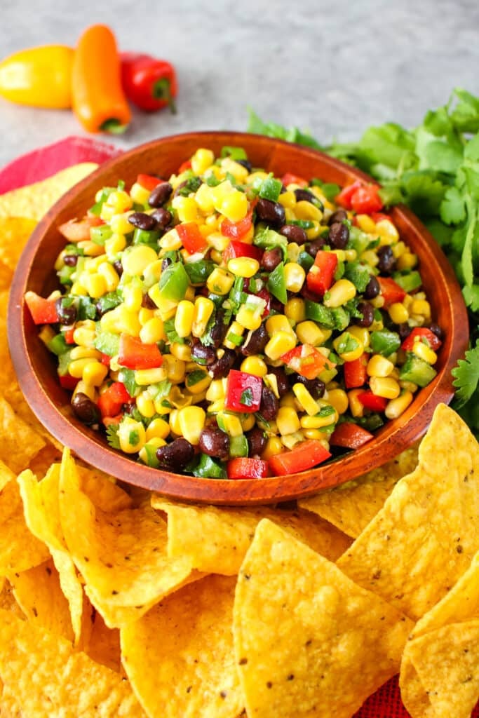 Corn and black bean salsa in a bowl with yellow corn chips on the side.