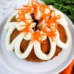 Carrot bundt cake topped with cream cheese frosting and carrot strands.