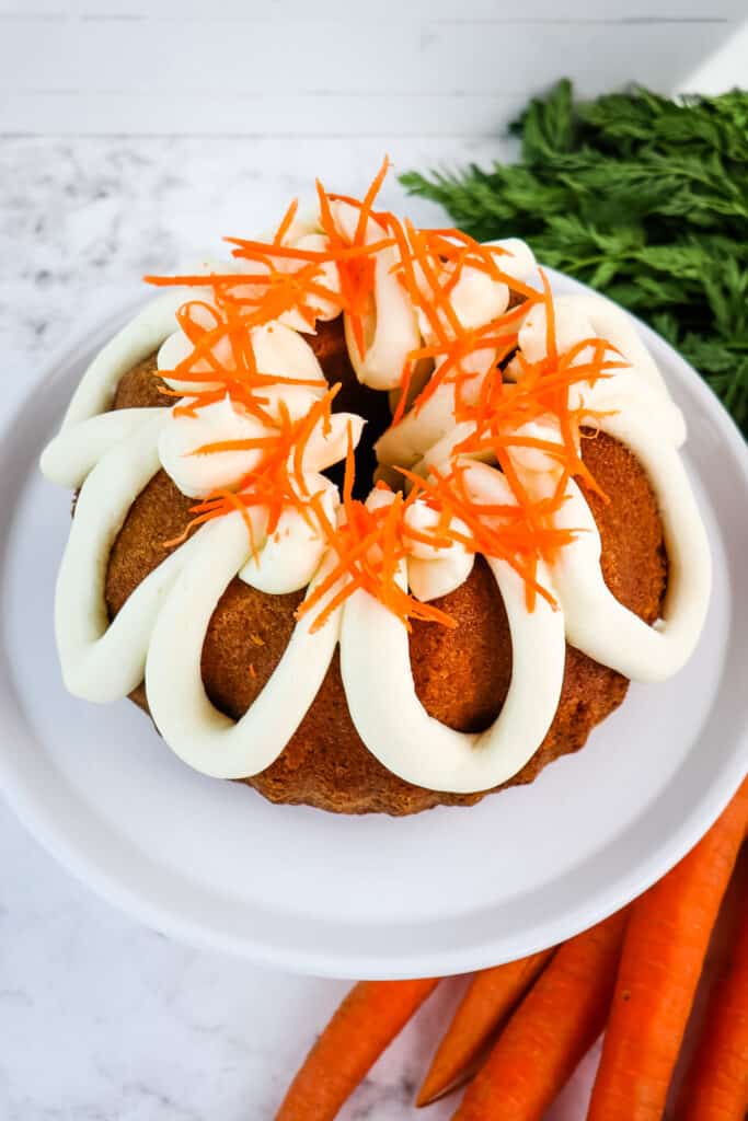 Carrot bundt cake topped with cream cheese frosting and carrot strands.