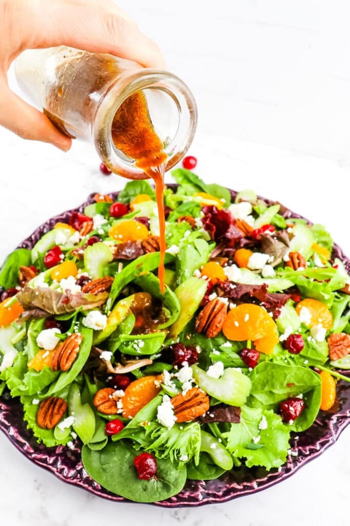 Honey balsamic vinaigrette being poured over cranberry citrus salad.