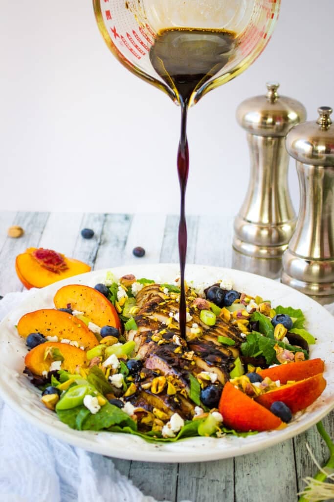 Honey balsamic vinaigrette being poured over balsamic chicken salad.