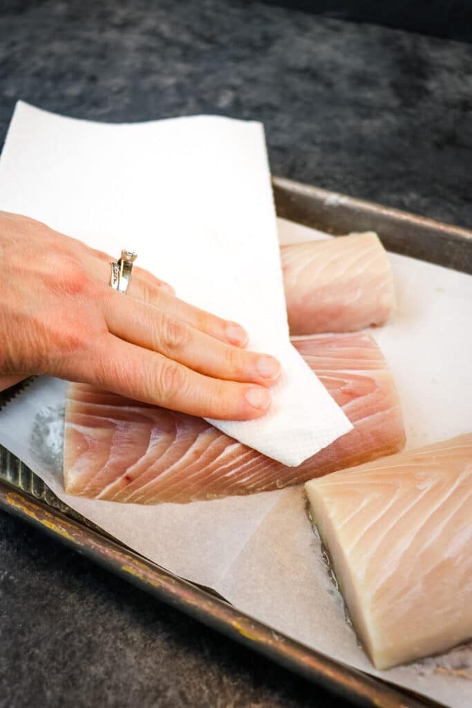 Prepping the mahi mahi fillets by patting them dry with paper towels.