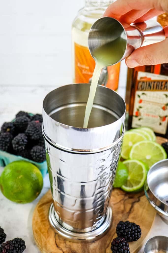 Lime juice being poured into cocktail shaker.