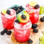 Three Blackberry margaritas with salted rim glasses topped with fresh blackberries and lime slices.