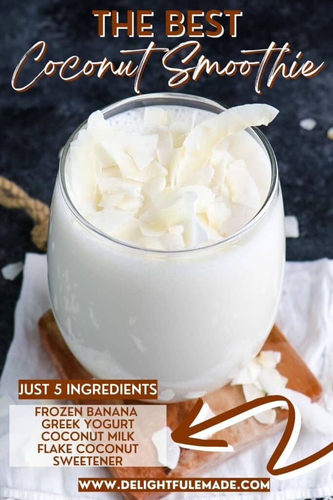 Coconut smoothie  in a clear glass topped with large flakes of coconut.