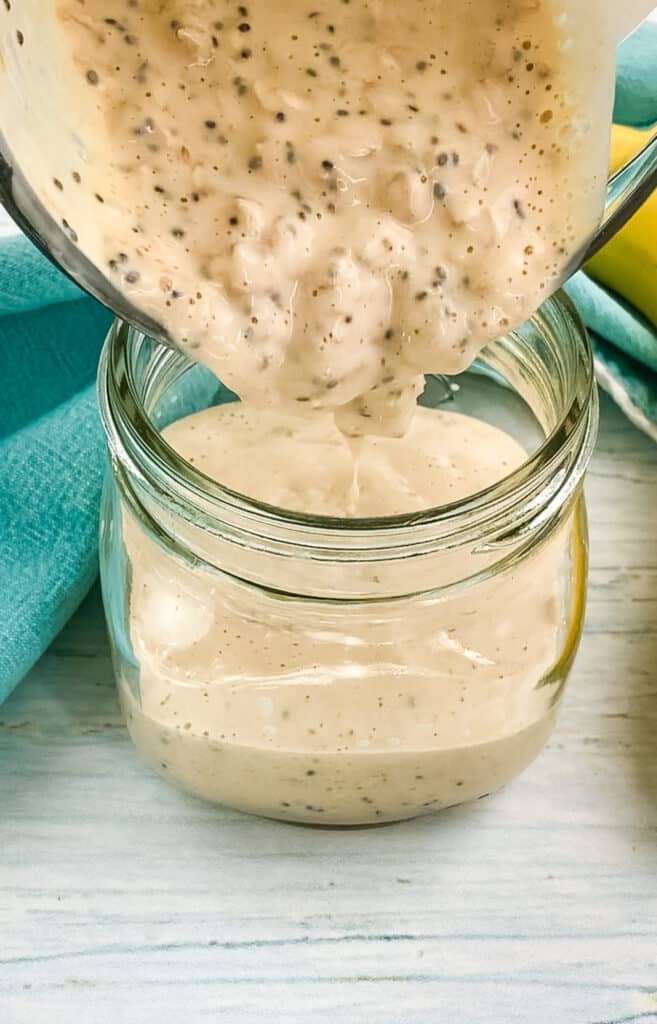 Peanut butter overnight oats being poured into a mason jar.