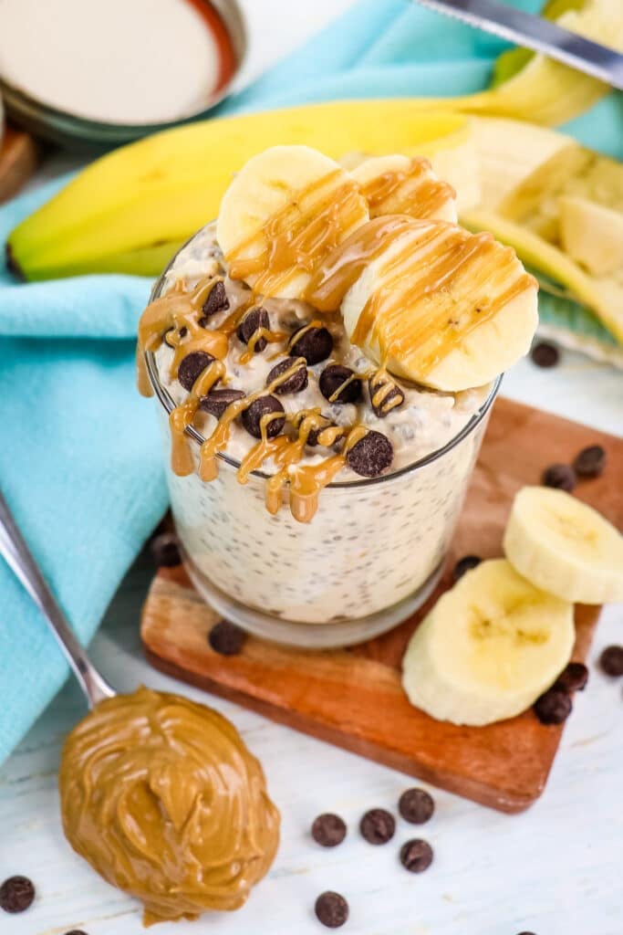 Peanut butter overnight oats in a glass with spoonful of creamy peanut butter on the side.