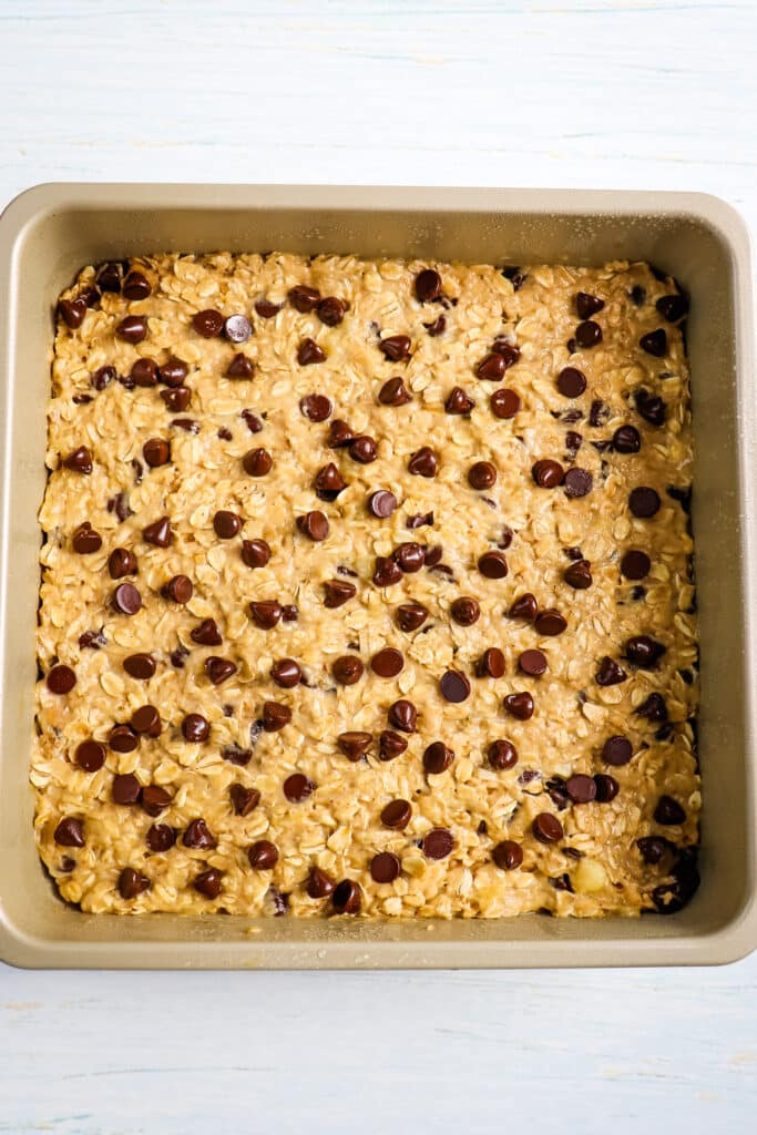 Peanut butter oatmeal bars batter pressed into pan and topped with chocolate chips.