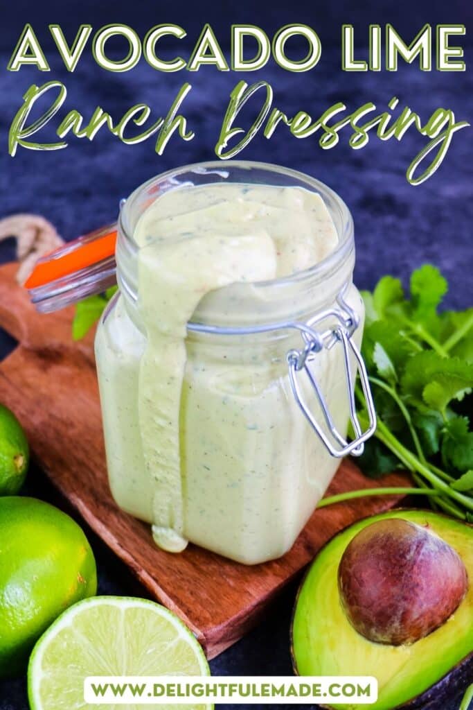 Avocado lime ranch dressing in a jar with sliced lime, avocado and cilantro on the side.