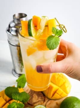 Mango mojito recipe in a glass and held in hand.