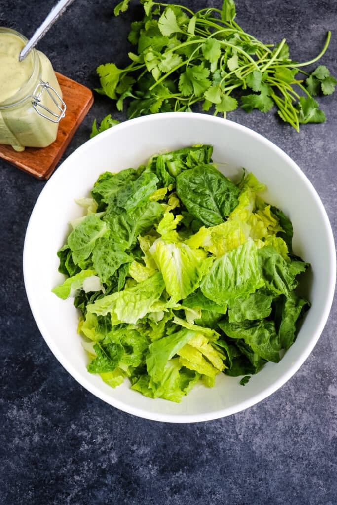 Romaine lettuce torn into pieces in a bowl to make southwest salad.