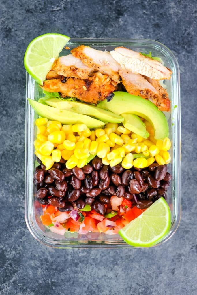 Southwest chicken salad with two lime wedges on the side, in a meal prep container.