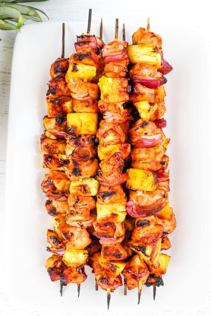 BBQ chicken skewers stacked on a platter.