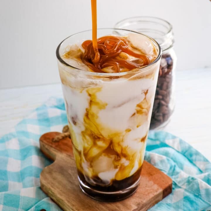Caramel sauce being drizzled over the top of the milk for making an iced caramel latte recipe.