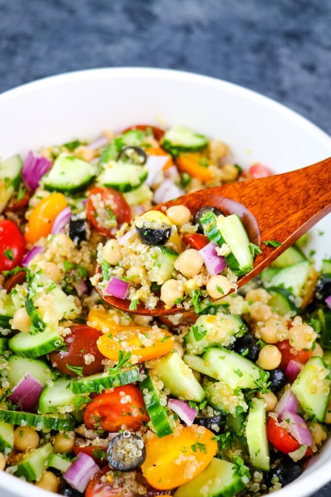 Quinoa chickpea salad in a bowl with wooden spoon scooping salad.