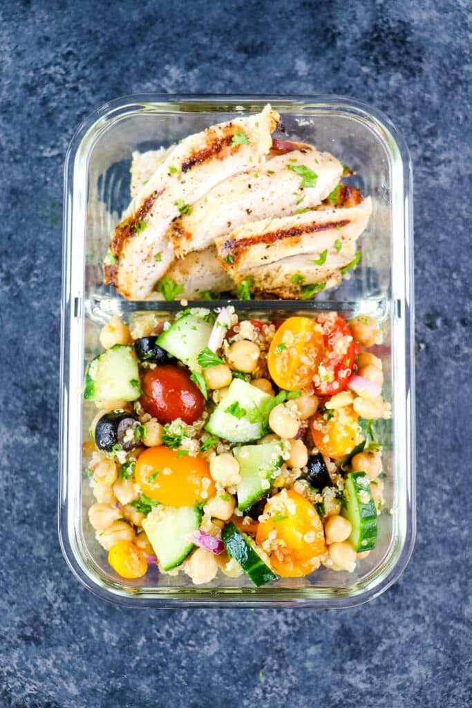 Quinoa chickpea salad in a meal prep container with grilled chicken.