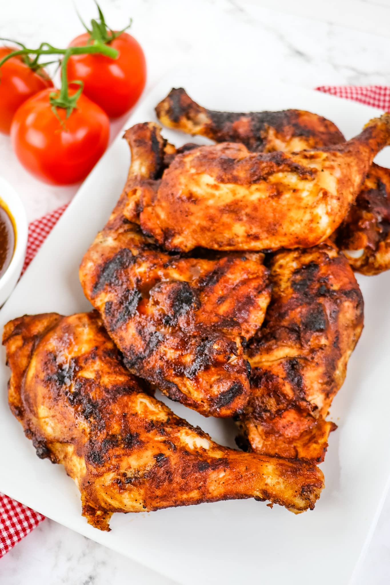 Grilled chicken quarters on a white platter.