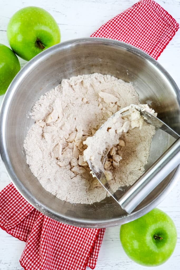 Dry ingredients being mixed with butter to make apple scones.