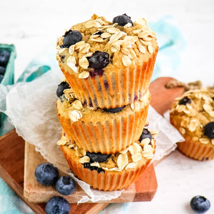 Three banana blueberry oatmeal muffins stacked on top of each other.