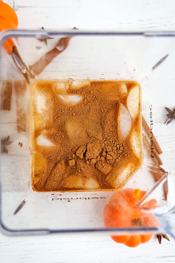 Ingredients for making a pumpkin spice frappuccino placed in a blender with ice.