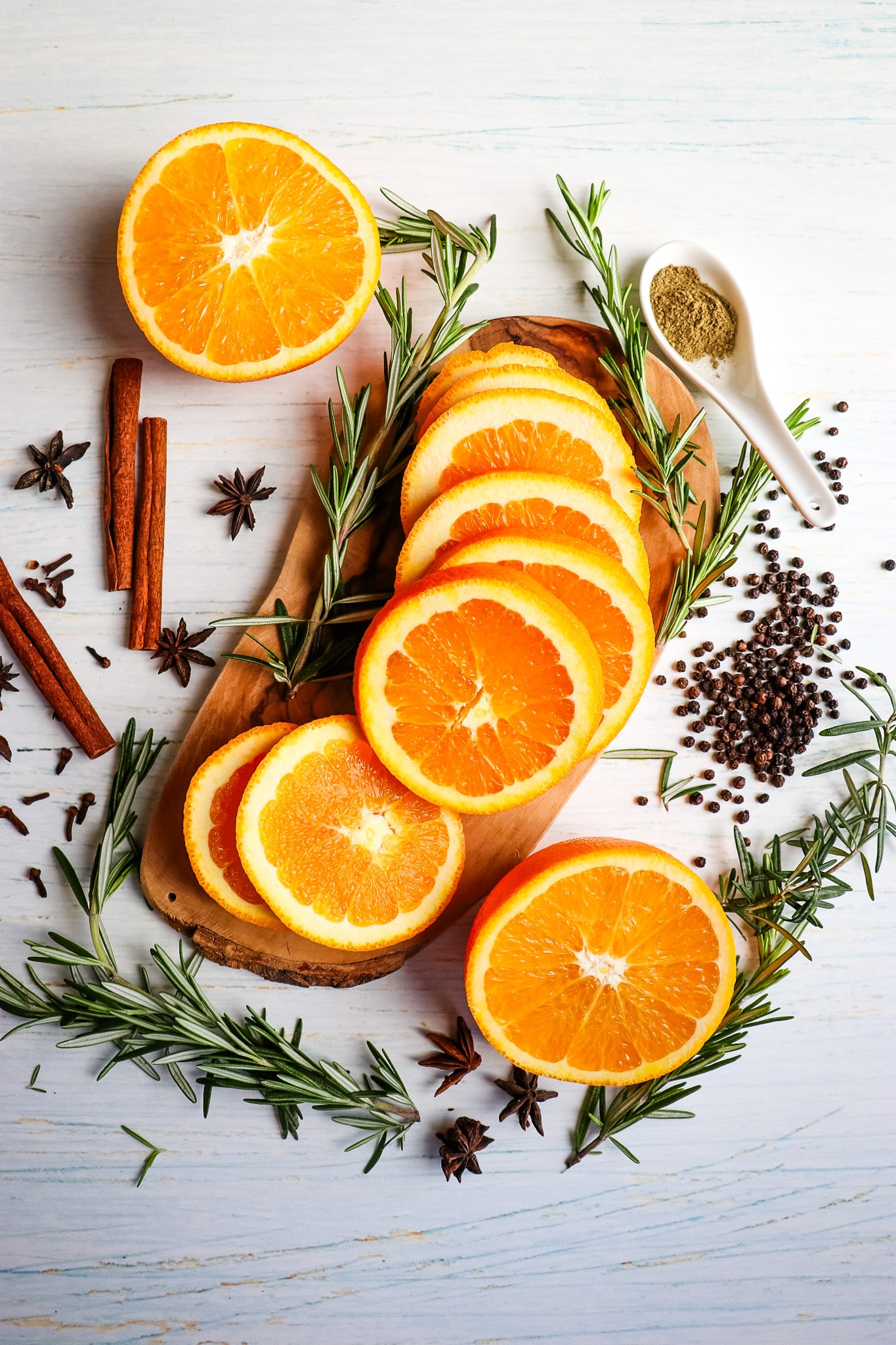 Ingredients needed to make a citrus turkey brine, with sliced oranges in the center and rosemary sprigs on the side.