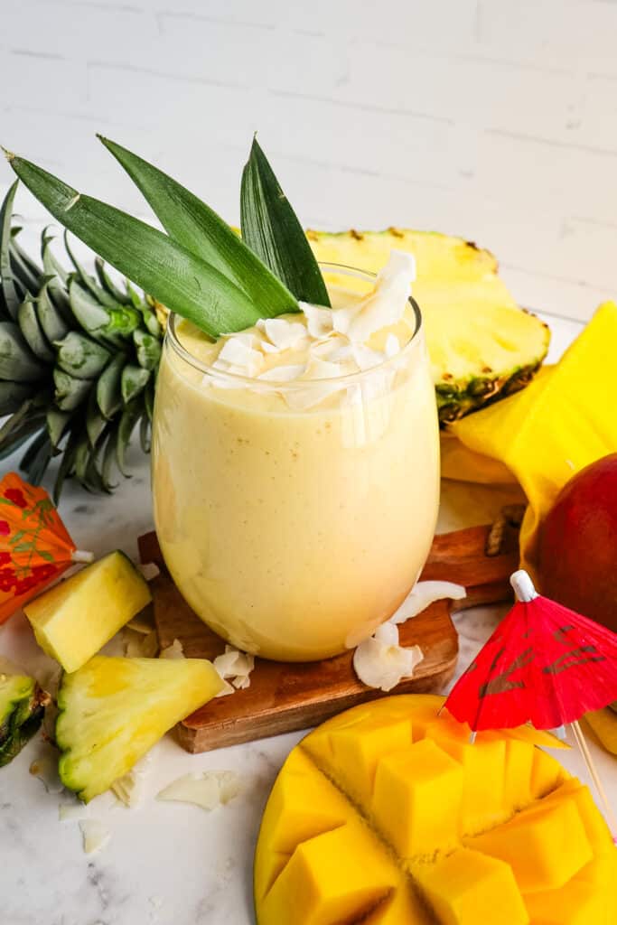 Pineapple mango smoothie topped with flake coconut and pineapple leaves.