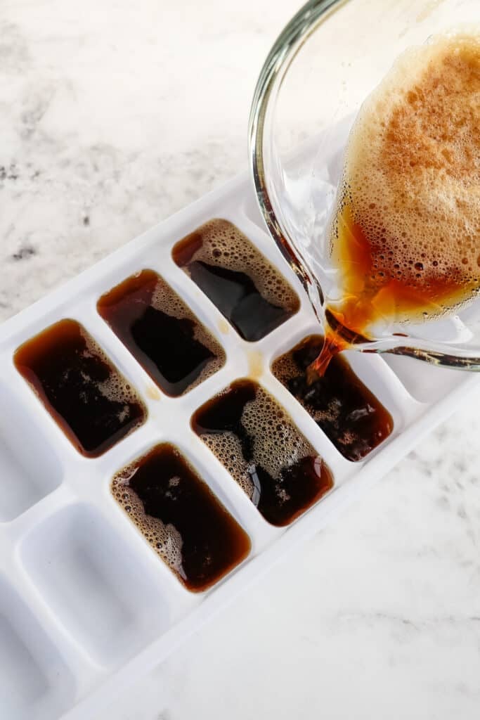 Coffee being poured into an ice cube tray for making coffee cubes.