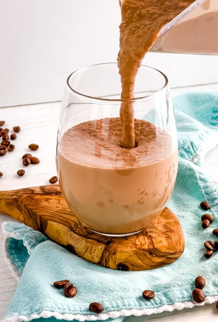 Cafe mocha smoothie being poured into a clear glass.