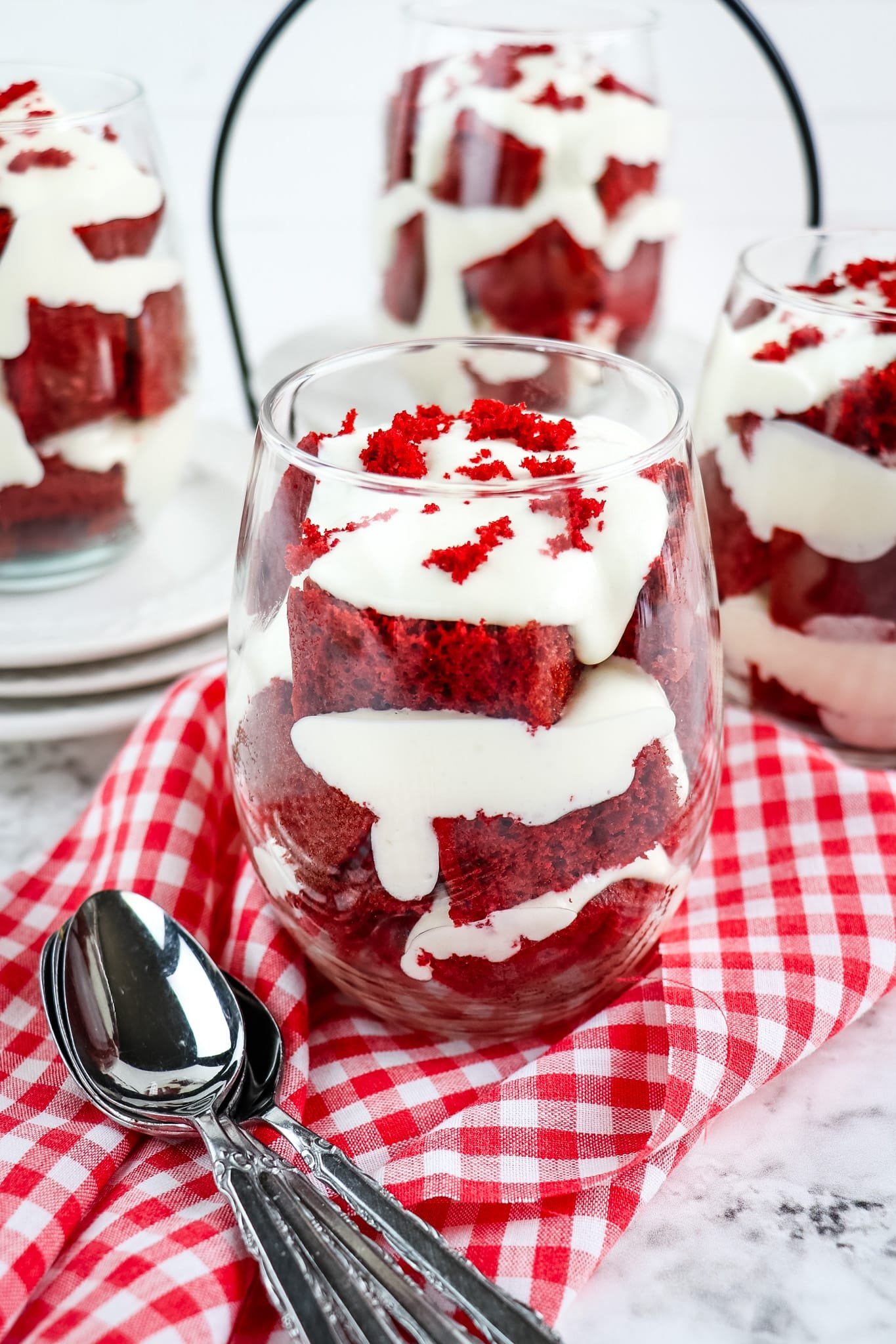 Red velvet cake parfait topped with red velvet cake crumbs with spoons on the side.
