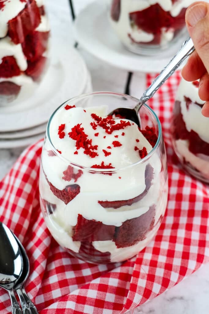 Red velvet parfait with cream cheese custard with a spoon taking a bite out of the dessert.