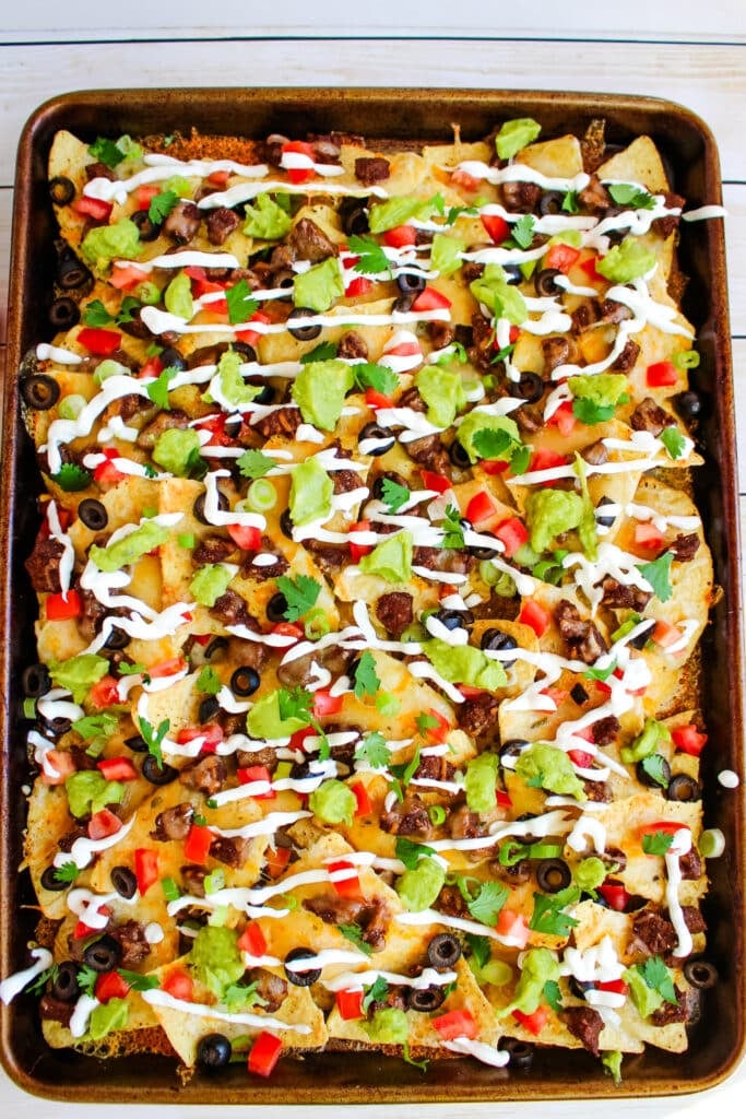 Steak nachos topped with sour cream, guacamole, tomatoes, olives and onions.