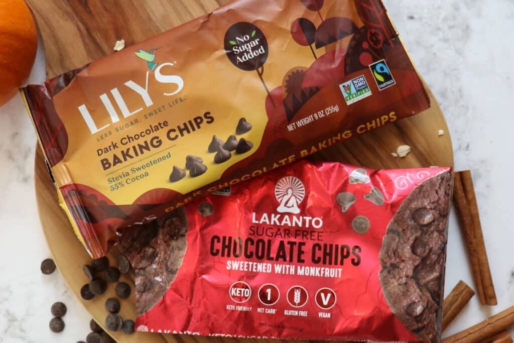 Bags of Lily's semi sweet chocolate chips and Lakanto chocolate chips on a board.